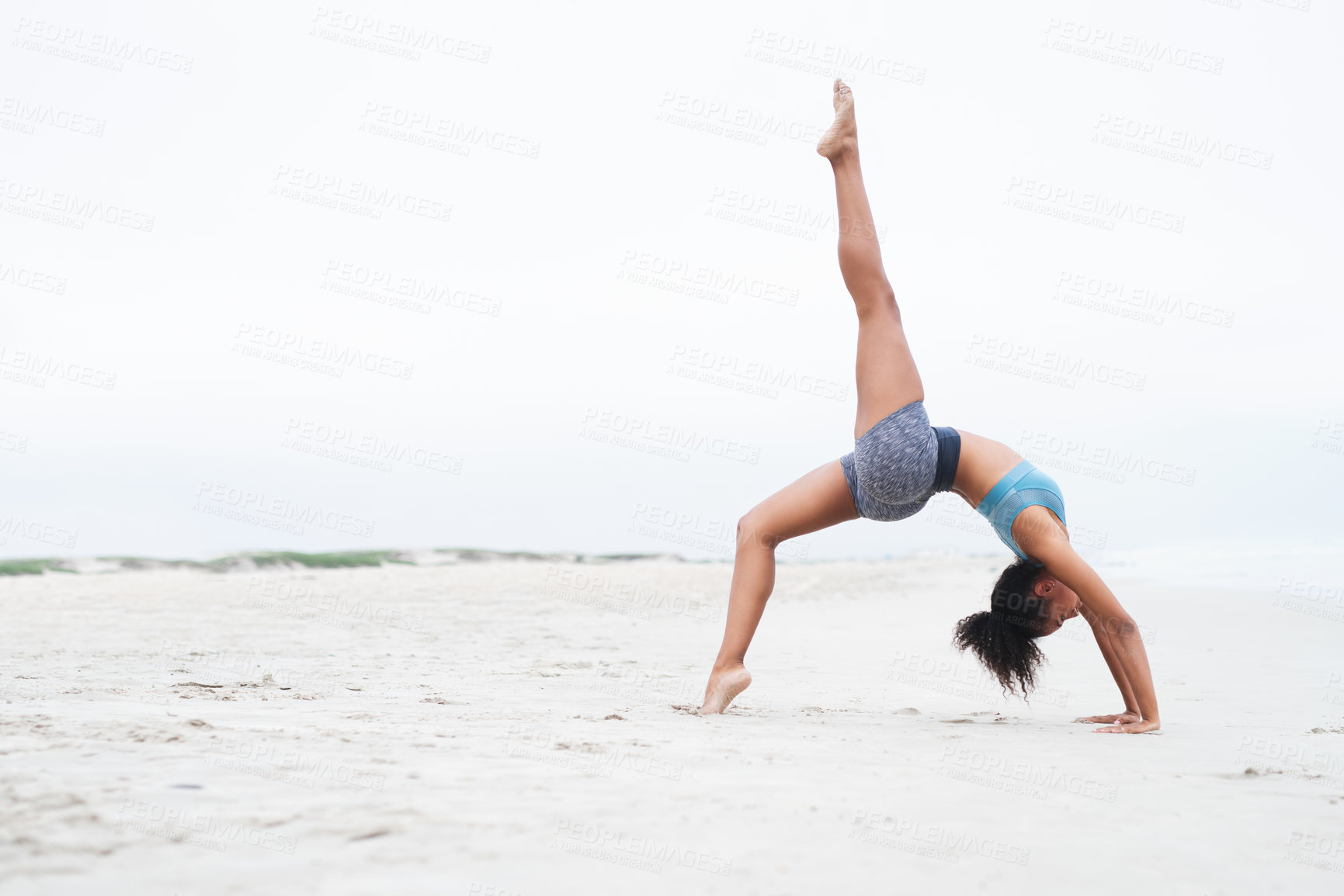 Buy stock photo Shot of a young woman doing a handstand at the beach