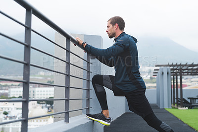 Buy stock photo Shot of a sporty young man stretching while exercising outdoors