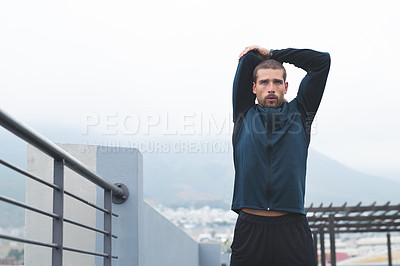 Buy stock photo Shot of a sporty young man stretching while exercising outdoors