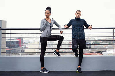 Buy stock photo Shot of a sporty young man and woman taking a break while exercising outdoors