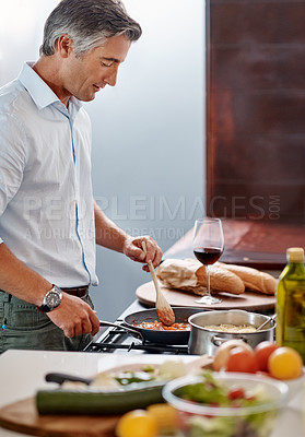 Buy stock photo Cropped shot of a handsome mature man cooking dinner in his kitchen at home