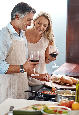 Buy stock photo Cropped shot of an affectionate mature couple drinking wine while cooking dinner in their kitchen at home