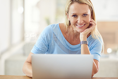 Buy stock photo Cropped portrait of an attractive mature woman sitting and using a laptop while in her living room during the day