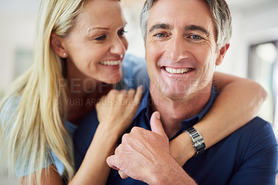 Buy stock photo Cropped portrait of an attractive mature woman hugging her handsome mature husband while he uses a laptop in the house