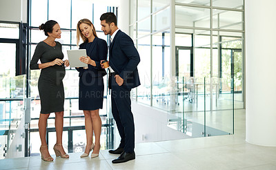 Buy stock photo Full length shot of a group of young businesspeople standing together in a modern office and using a tablet