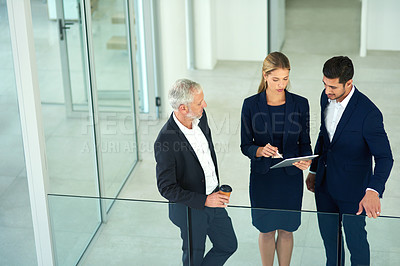 Buy stock photo Cropped shot of a group of young businesspeople standing together in a modern office and using a tablet