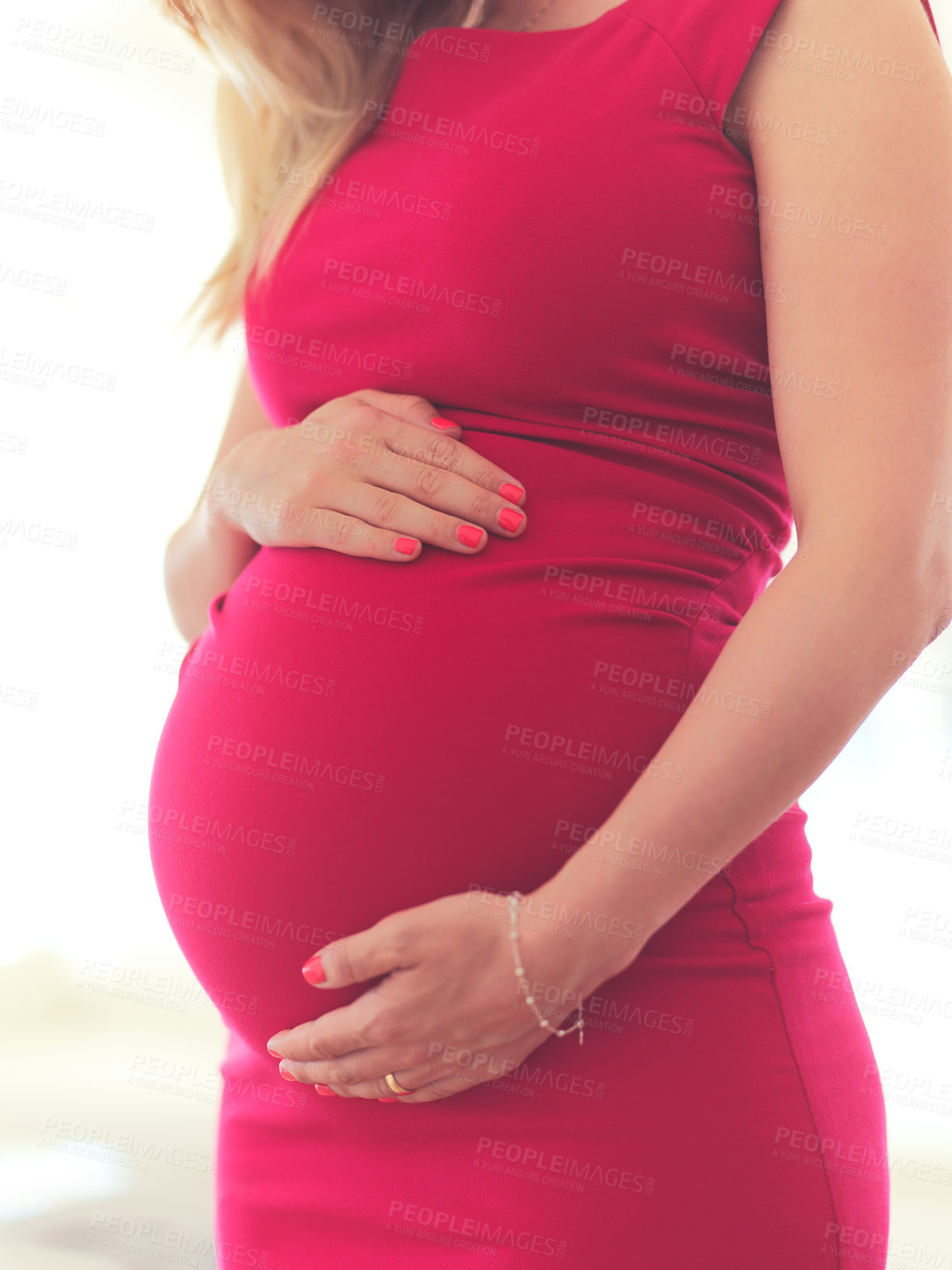 Buy stock photo Cropped shot of an unrecognizable pregnant young woman holding her belly while standing in her home