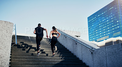 Buy stock photo Rearview shot of a young man and woman running up stairs together in the city