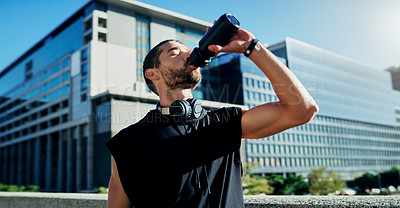 Buy stock photo Shot of a young man drinking water during his workout in the city