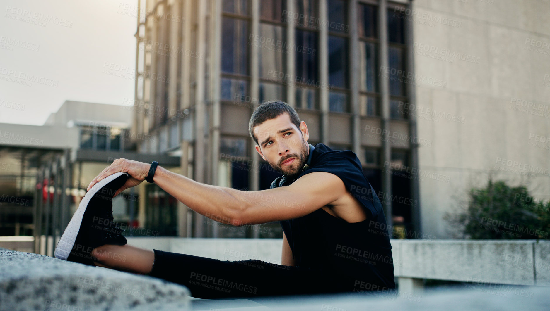 Buy stock photo Shot of a young man stretching during his workout in the city