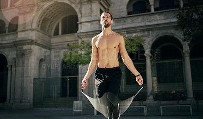 Buy stock photo Shot of a young man working out with a jump rope in the city