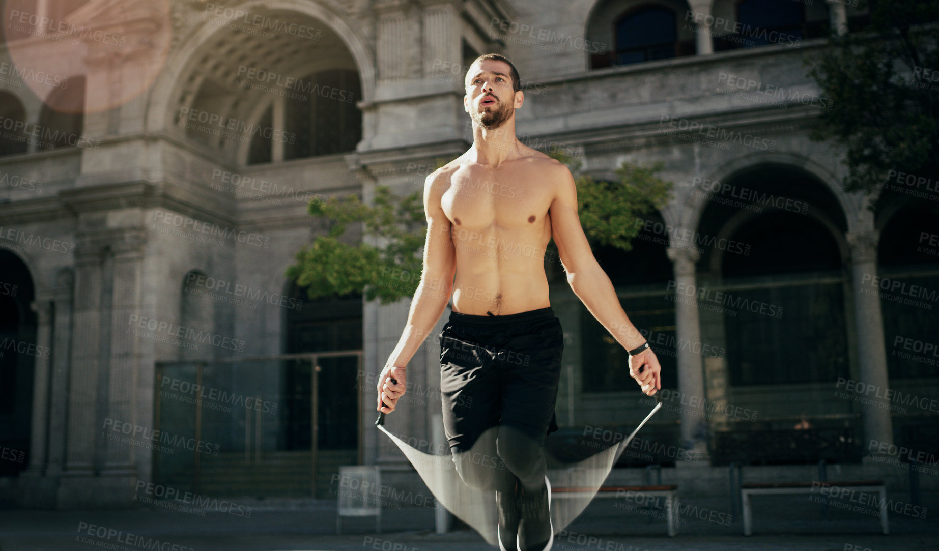 Buy stock photo Shot of a young man working out with a jump rope in the city