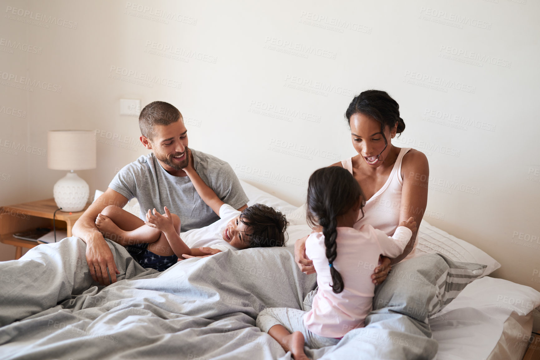 Buy stock photo Happy, relax and parents with children in bedroom for bonding, love and playful relationship. Family, childhood and mother, father and kids tickle for laughing, fun or playing on bed together in home