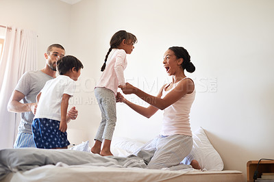 Buy stock photo Shot of a beautiful young family of four having fun and spending time together in their bedroom at home