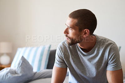Buy stock photo Shot of a handsome young man looking thoughtful in his bedroom at home