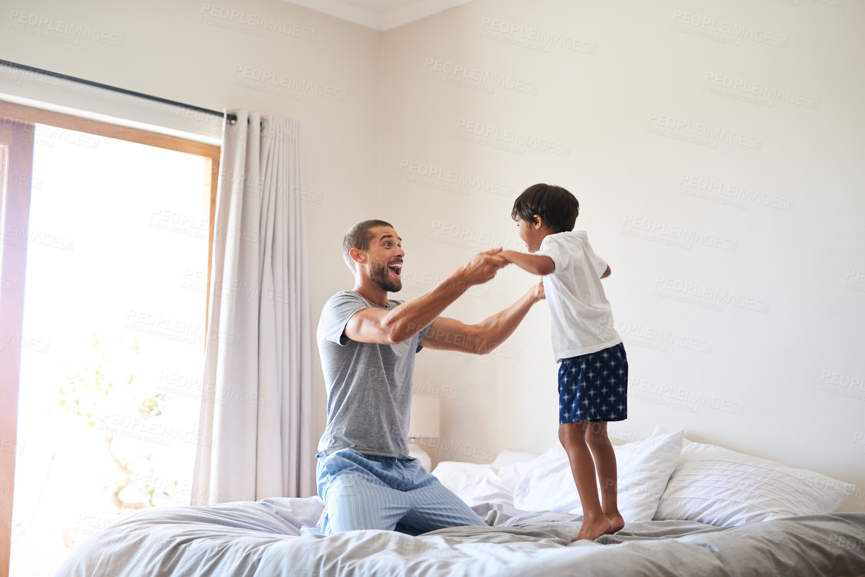 Buy stock photo Shot of a cheerful father and son playing together in the bedroom at home