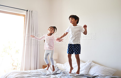 Buy stock photo Full length shot of a young brother and sister jumping on bed together at home