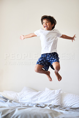 Buy stock photo Full length shot of an adorable little boy playing and jumping on a bed at home