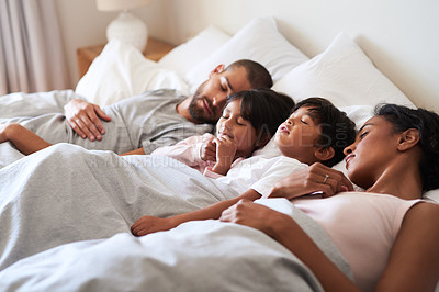 Buy stock photo Shot of a beautiful young family of four fast asleep in bed together in their bedroom at home