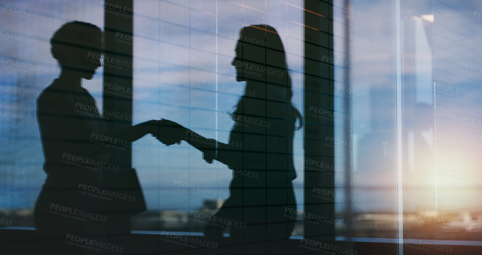 Buy stock photo Silhouette shot of two businesspeople shaking hands inside an office building