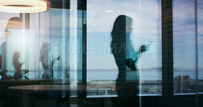 Buy stock photo Silhouette shot of a business woman using her cellphone inside of an office building