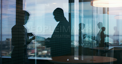 Buy stock photo Silhouette shot of two businesspeople having a discussion inside an office building
