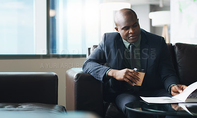 Buy stock photo Cropped shot of a businessman enjoying a cup of coffee while looking at paperwork