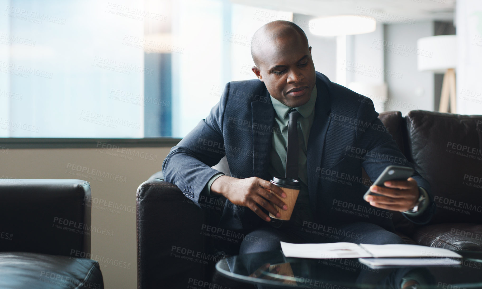 Buy stock photo Shot of a businessman using his cellphone while sitting in a modern office