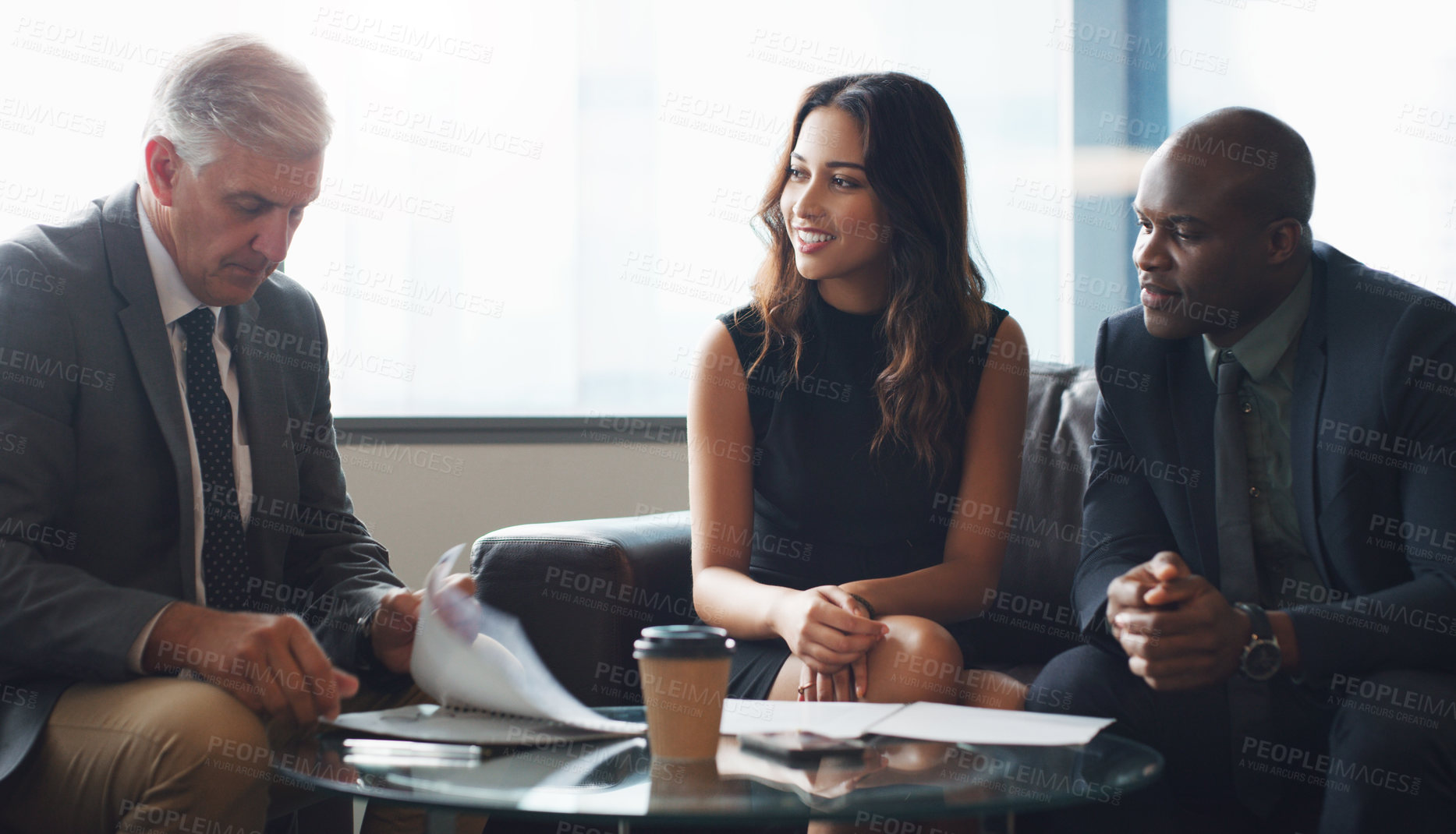 Buy stock photo Shot of a group of businesspeople having a discussion while sitting together on a couch at the office