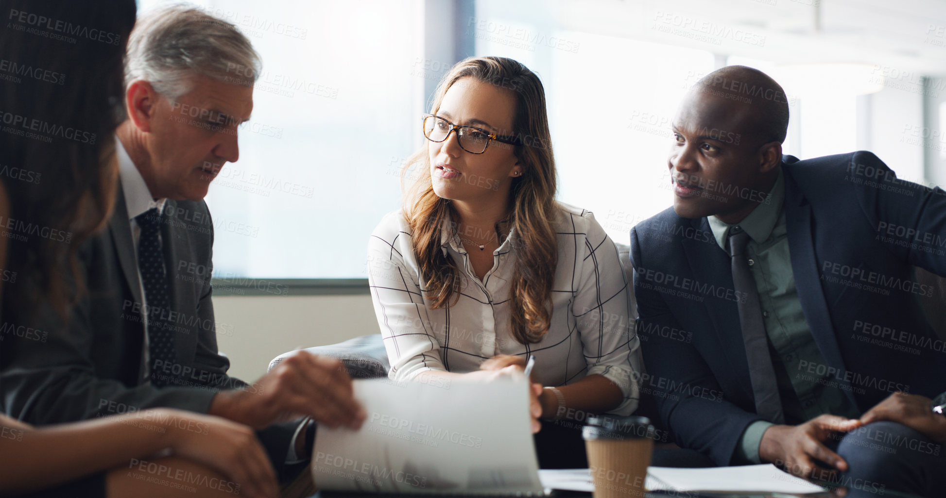 Buy stock photo Shot of a group of businesspeople having a discussion while sitting together on a couch at the office