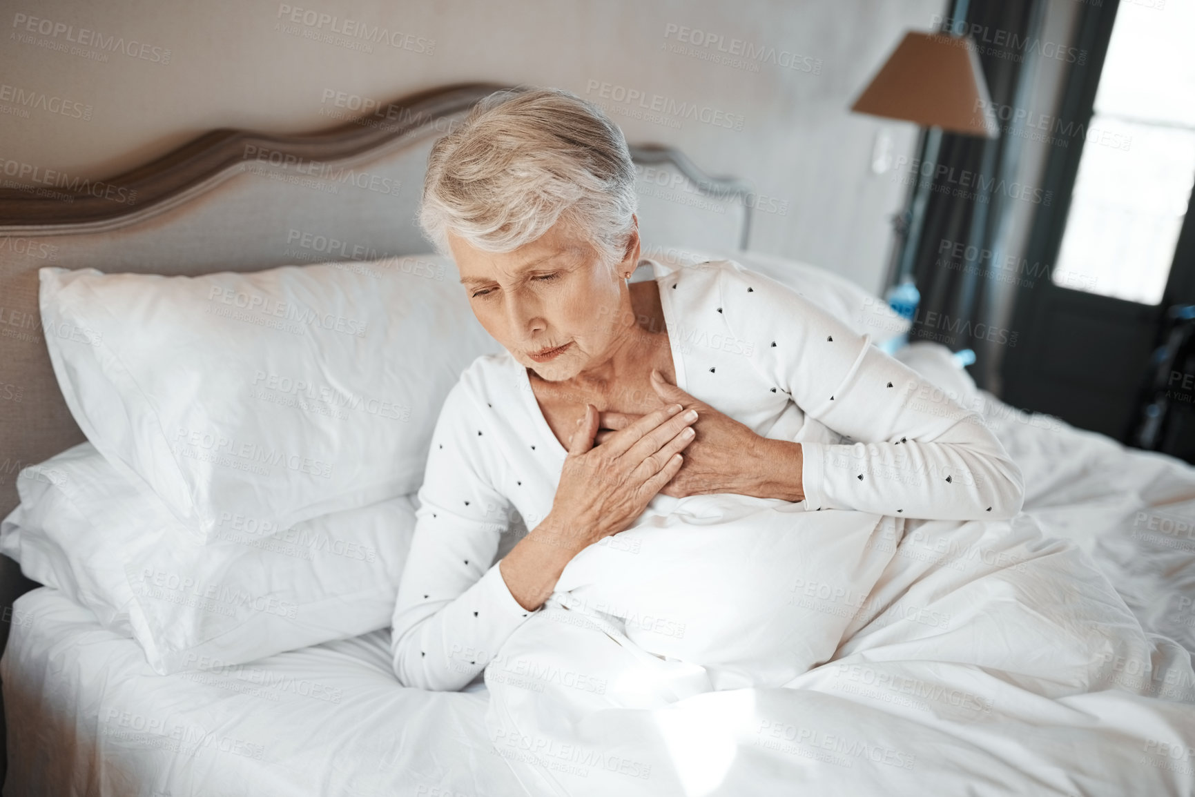 Buy stock photo Shot of a senior woman experiencing chest pain in bed in a nursing home