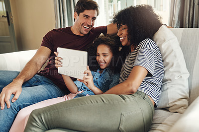 Buy stock photo Shot of a beautiful young family of three using a digital tablet while relaxing on a couch together at home