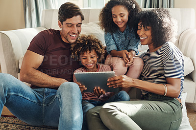 Buy stock photo Shot of a beautiful young family of four using a digital tablet together while relaxing on a sofa at home