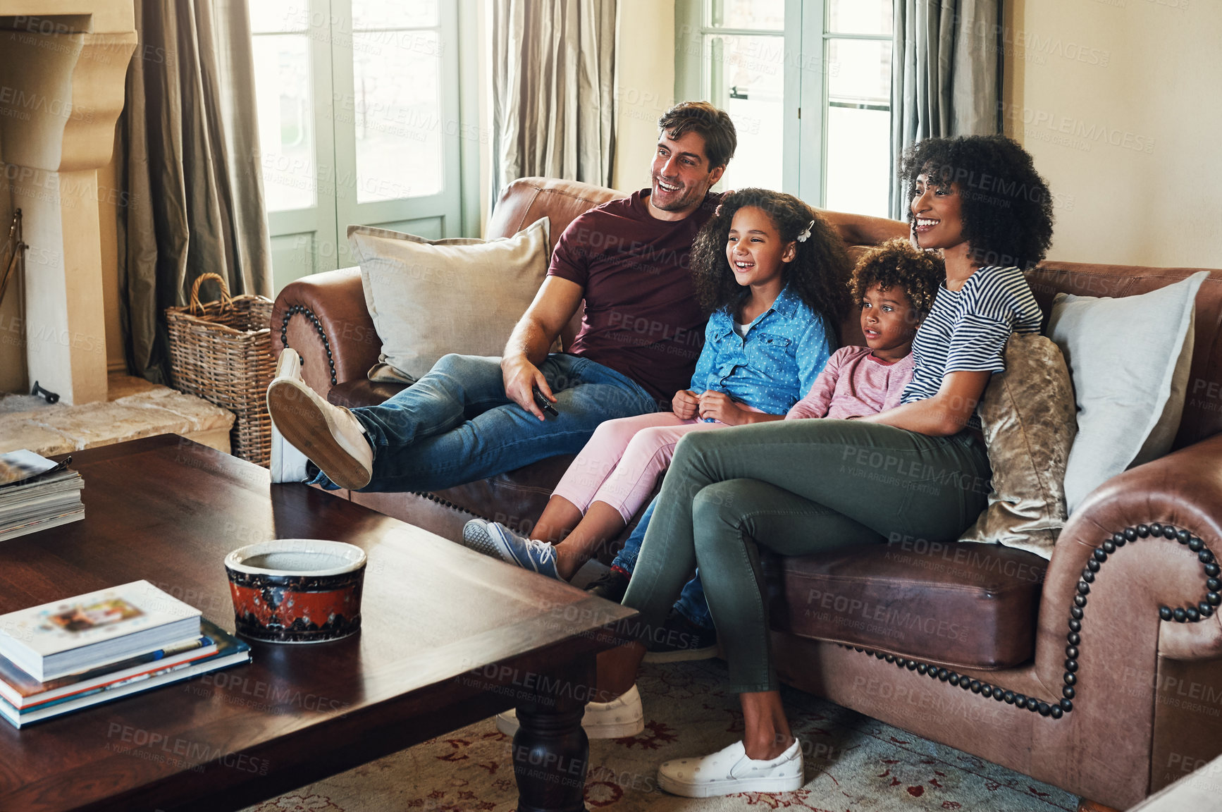 Buy stock photo Full length shot of a beautiful young family of four watching tv together at home