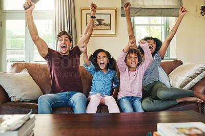 Buy stock photo Shot of a beautiful young family of four celebrating while watching tv together at home