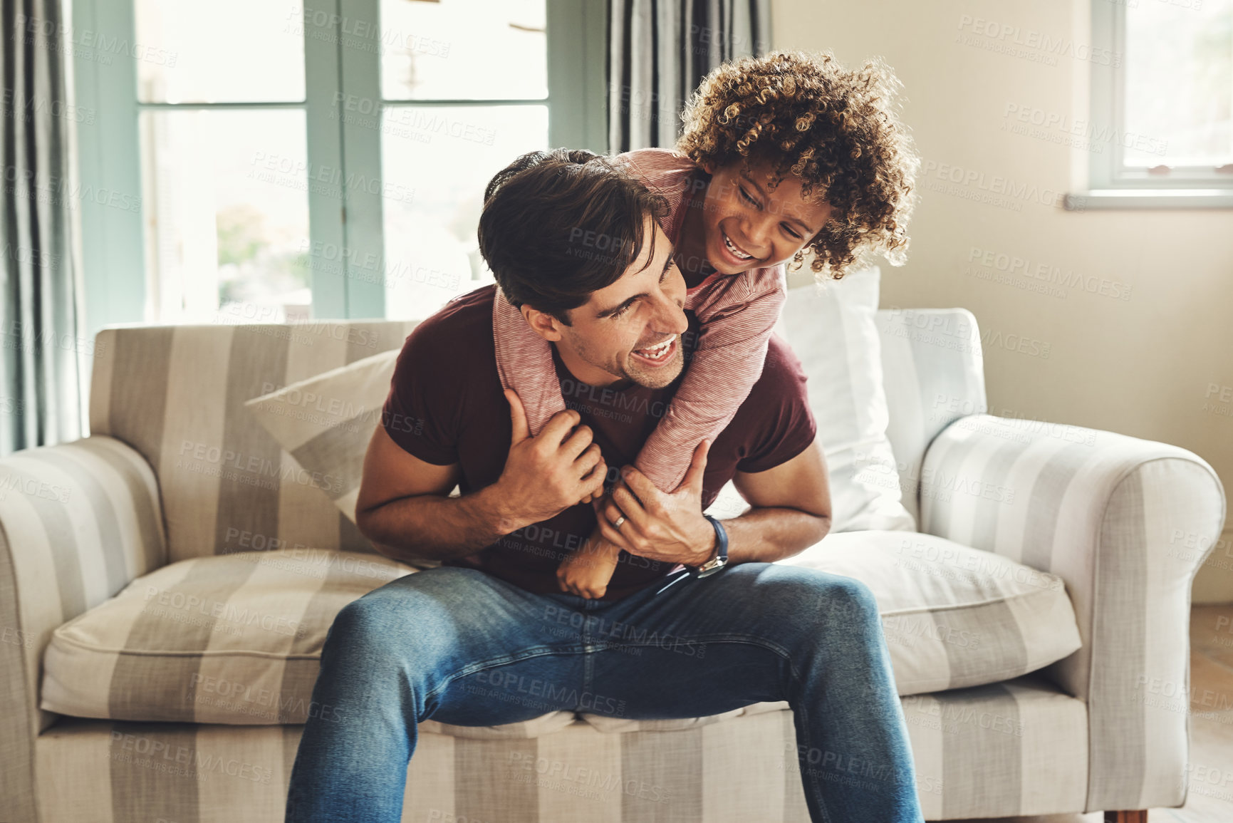 Buy stock photo Shot of a happy young father and son playing together on a couch at home