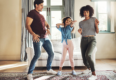 Buy stock photo Full length shot of a happy young family of three dancing together at home