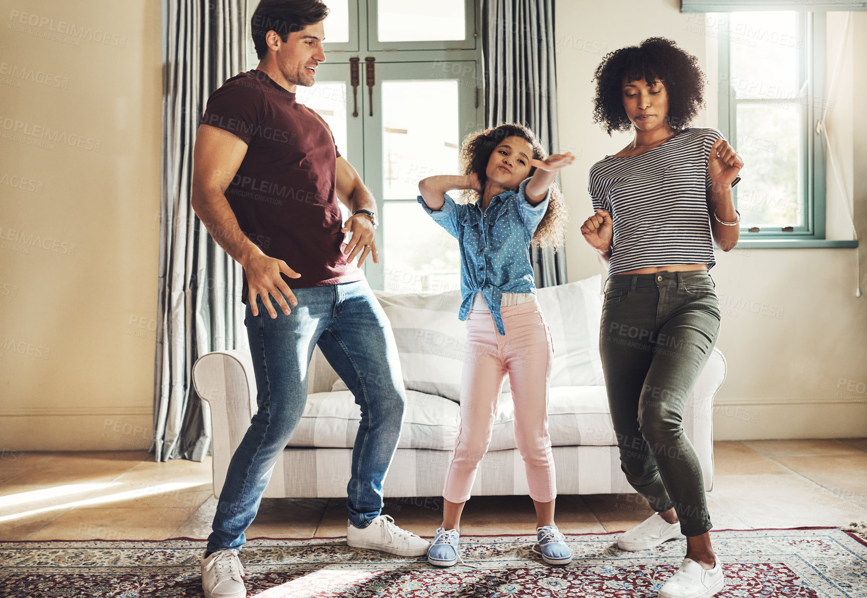 Buy stock photo Full length shot of a happy young family of three dancing together at home