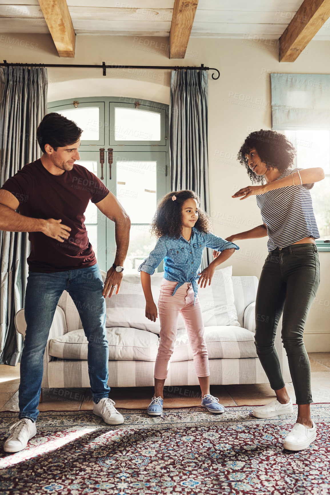 Buy stock photo Full length shot of a happy young family of three dancing together at home