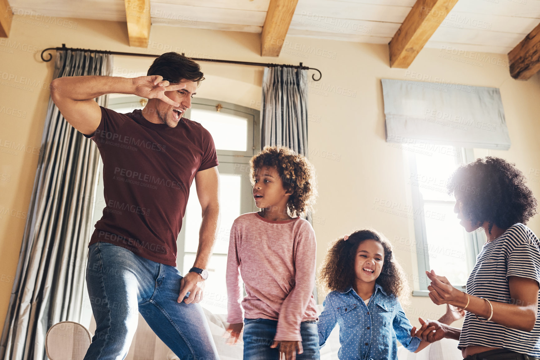 Buy stock photo Shot of a happy young family of four dancing together at home