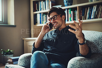 Buy stock photo Shot of a handsome young businessman taking a phone call in his office at home