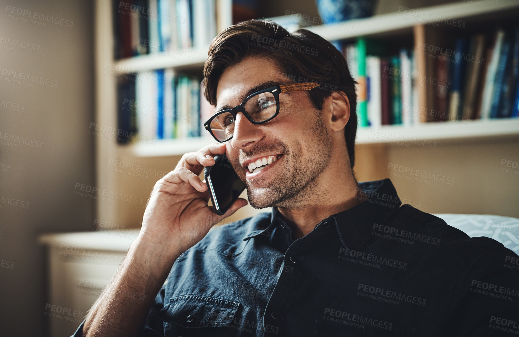 Buy stock photo Shot of a handsome young businessman making a phone call in his office at home