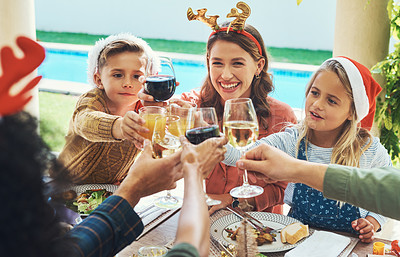 Buy stock photo Shot of a beautiful young family joining their glasses for a toast at a Christmas lunch party