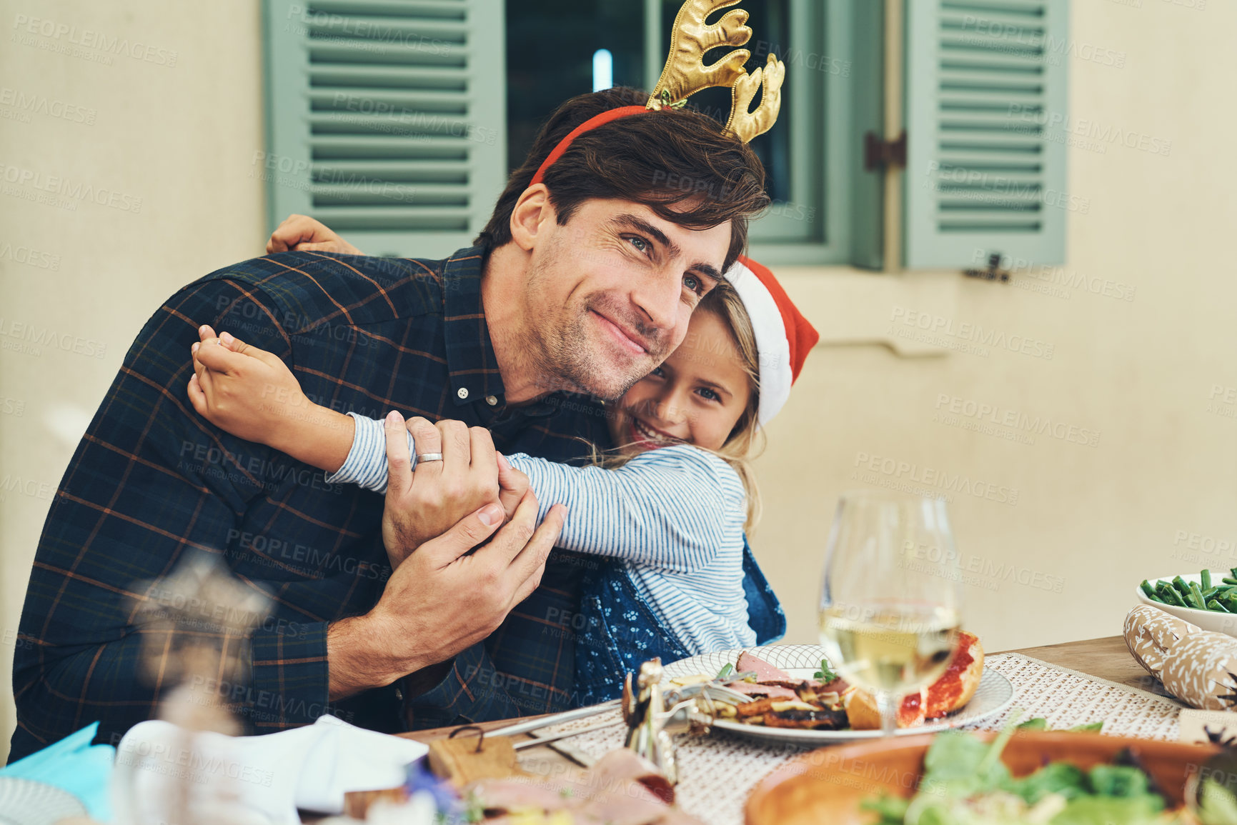 Buy stock photo Shot of an adorable little girl celebrating Christmas over lunch with her father at home