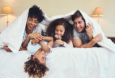 Buy stock photo Family, parents and happy children with blanket on bed for bonding, connection and playing with laughing. Interracial, love and funny game in bedroom with care, relax and resting in home in morning