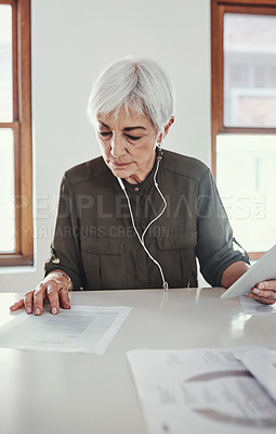 Buy stock photo Cropped shot of an attractive mature businesswoman reading through paperwork in her office