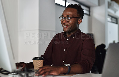 Buy stock photo Cropped shot of a handsome young businessman sitting alone and using his computer in the office
