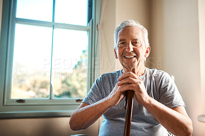 Buy stock photo Cropped portrait of a happy senior man sitting and holding his walking stick in a nursing home during the morning