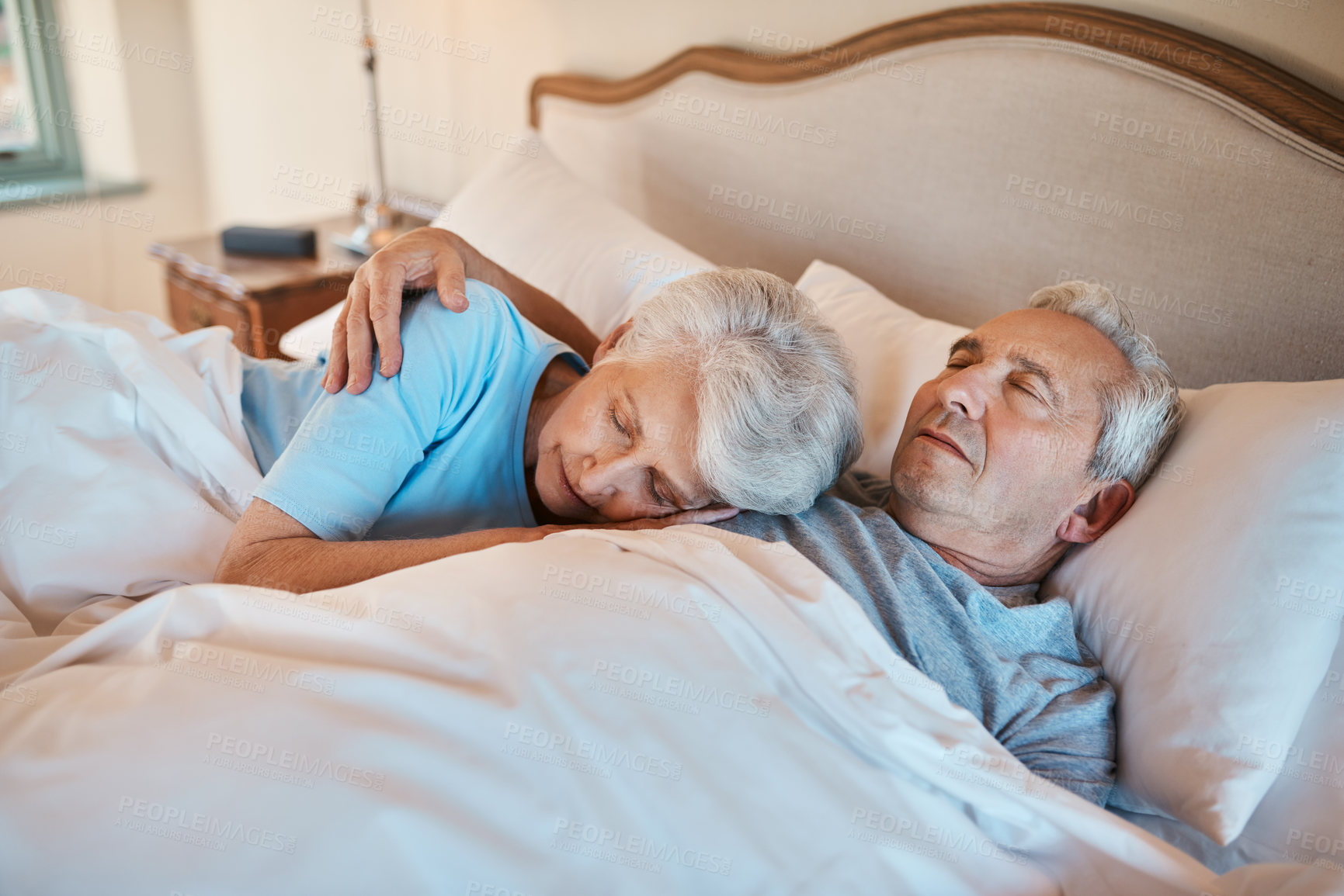 Buy stock photo Cropped shot of an affectionate senior couple cuddling each other while asleep in bed at a nursing home