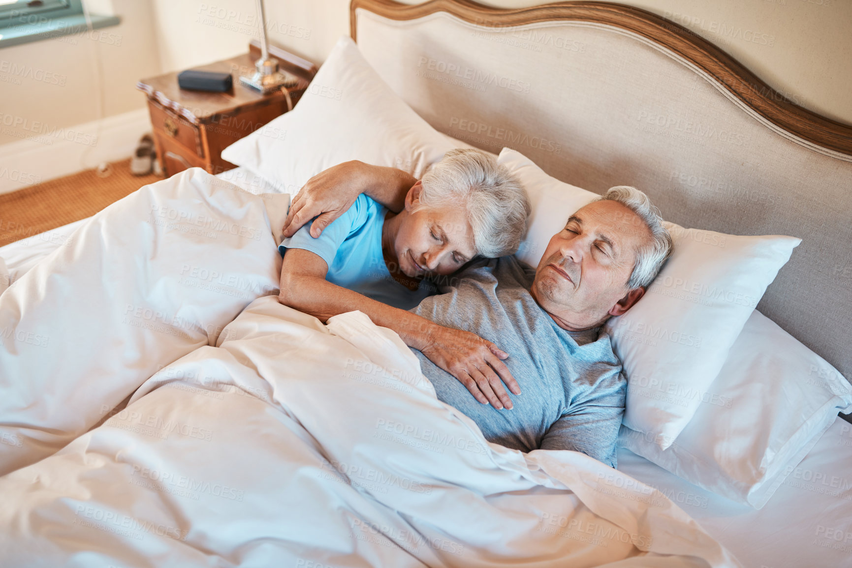 Buy stock photo Cropped shot of an affectionate senior couple cuddling each other while asleep in bed at a nursing home